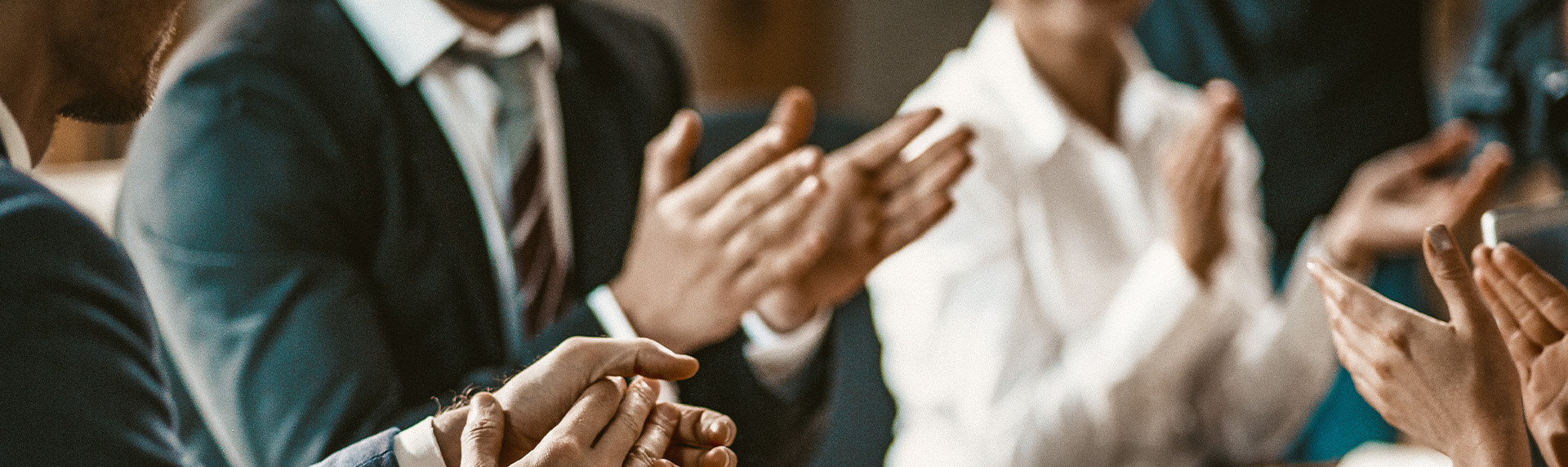 A group of people, dressed in business attire, are seated and applauding. The focus is on their hands, with blurred faces in the background, suggesting a professional setting like a mediation session or meeting where valuable tips are being shared.