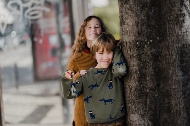 two children behind a tree