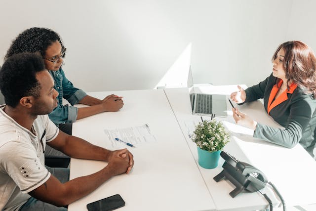 three people sitting at a table having a discussion