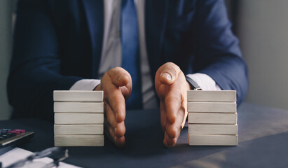A person in a suit divides two stacks of wooden blocks on a desk with their hands, symbolizing the organization or separation of a family business after divorce.